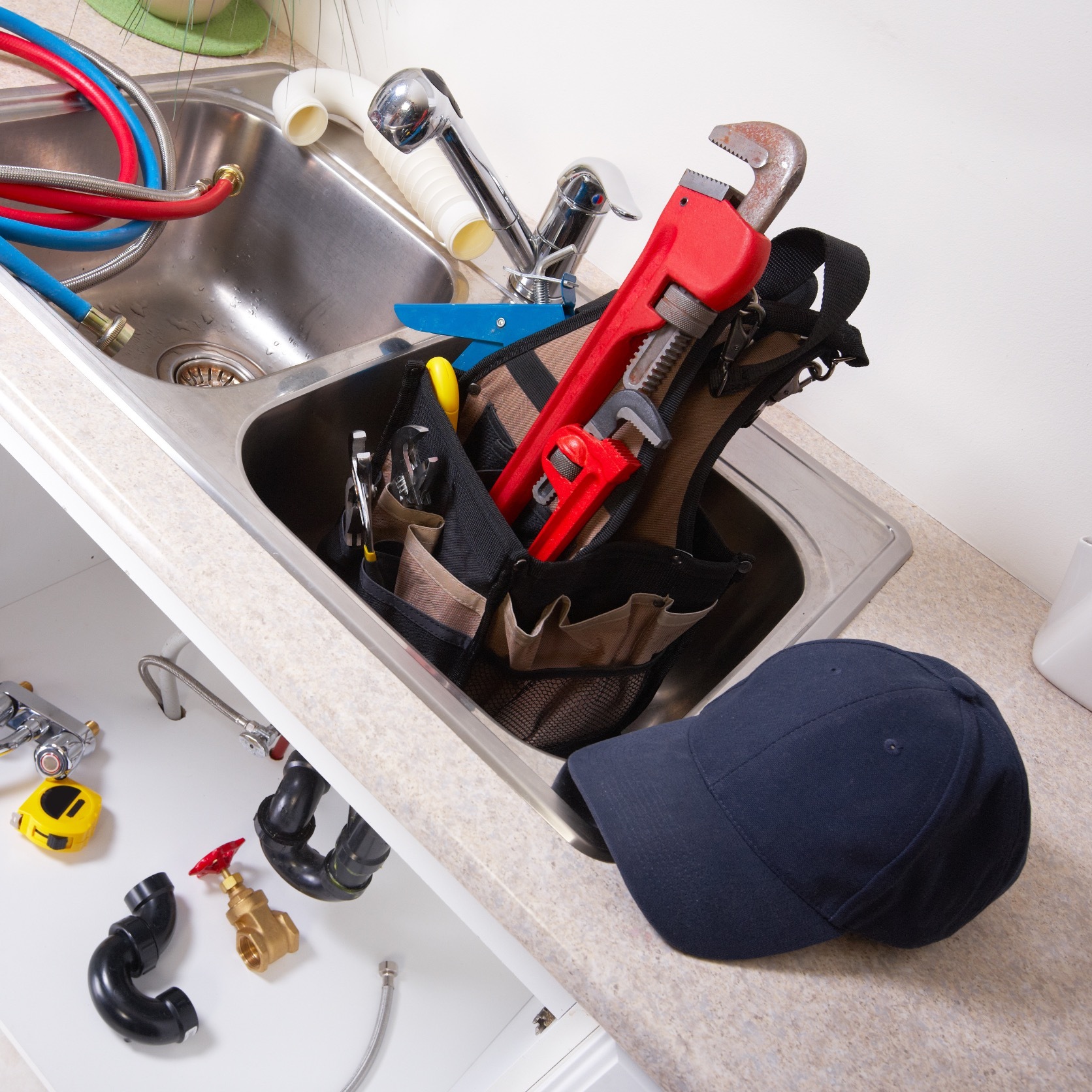 plumbing tools and hat near a sink